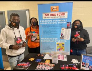 Three people standing in front of a table with flyers.